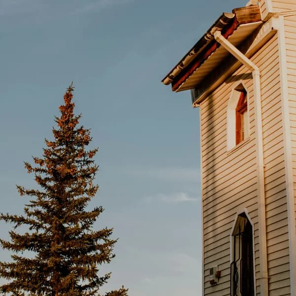 Wooden church building with autumn tree against clear blue sky
