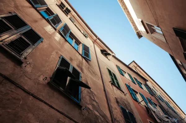 Weathered brick building facade with blue-shuttered windows needing cleaning maintenance