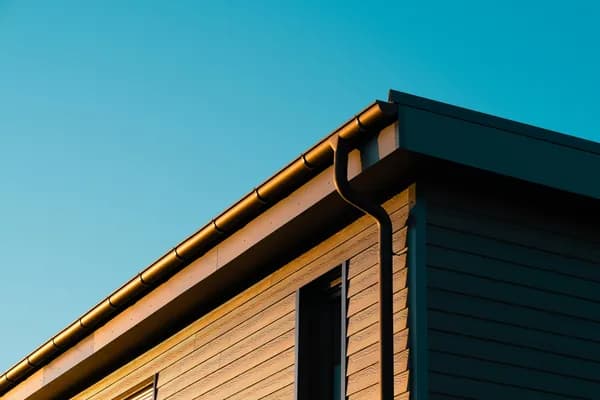 Modern building exterior with metal gutters and downspout against clear blue sky
