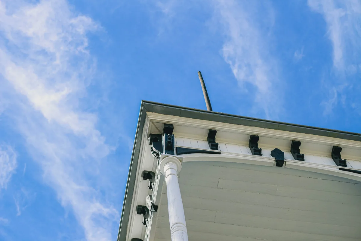 Worker on ladder cleaning exterior windows of white building against blue sky