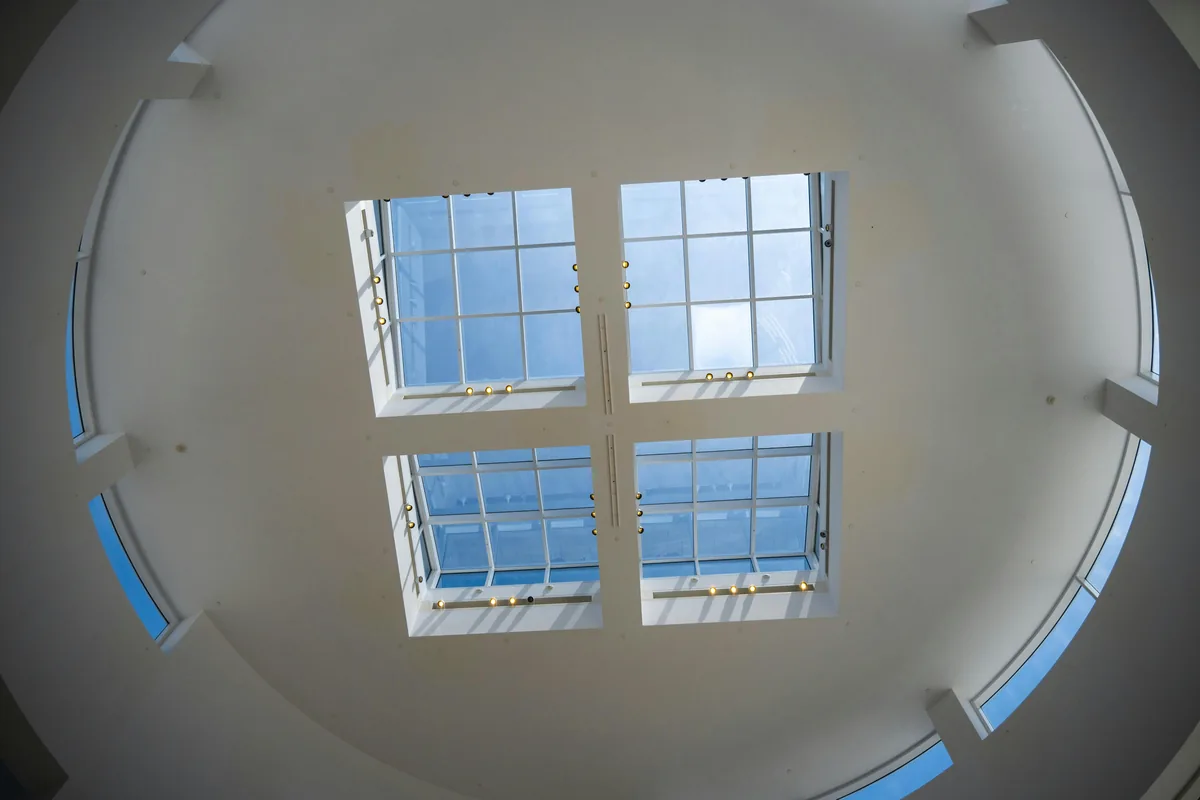 Four large windows in white frames on curved interior ceiling with blue sky view