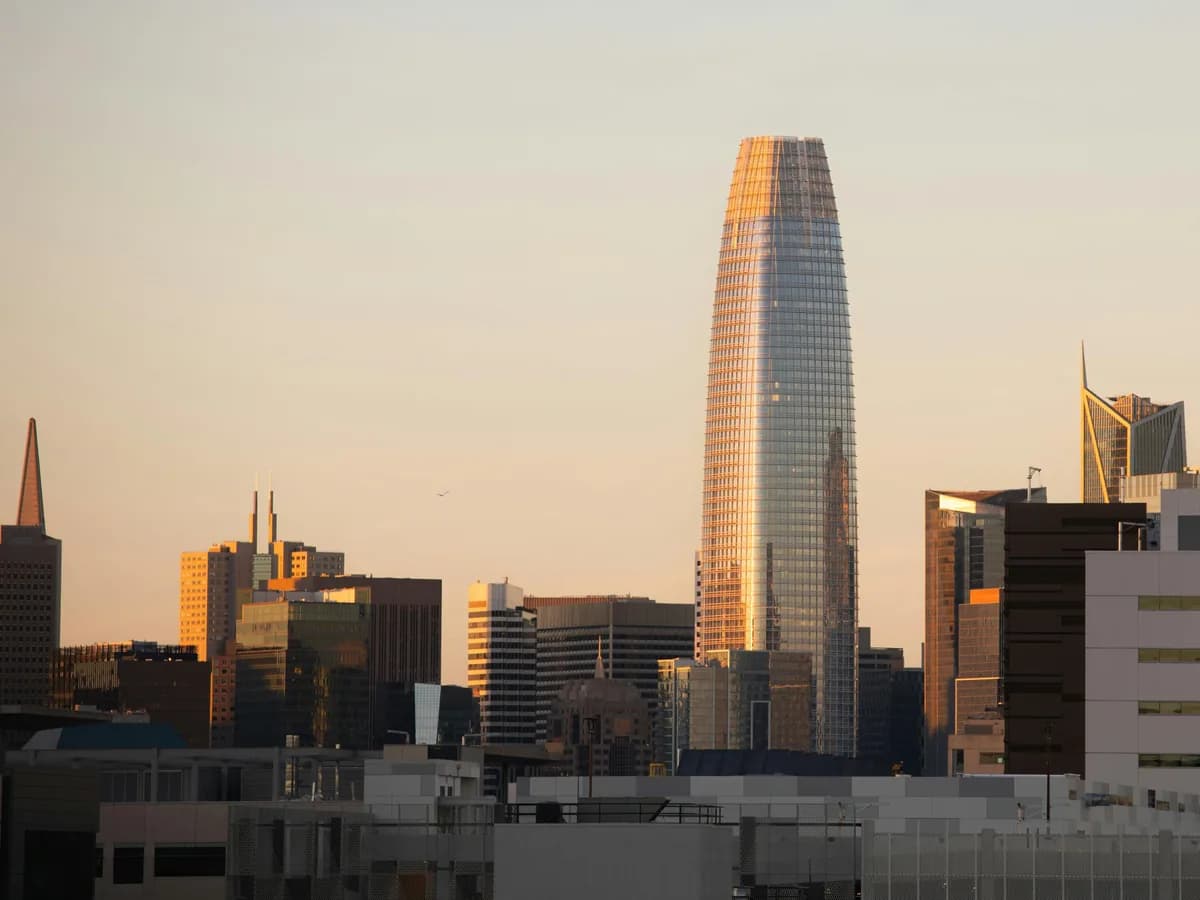Tall modern skyscraper among downtown buildings at golden hour sunset