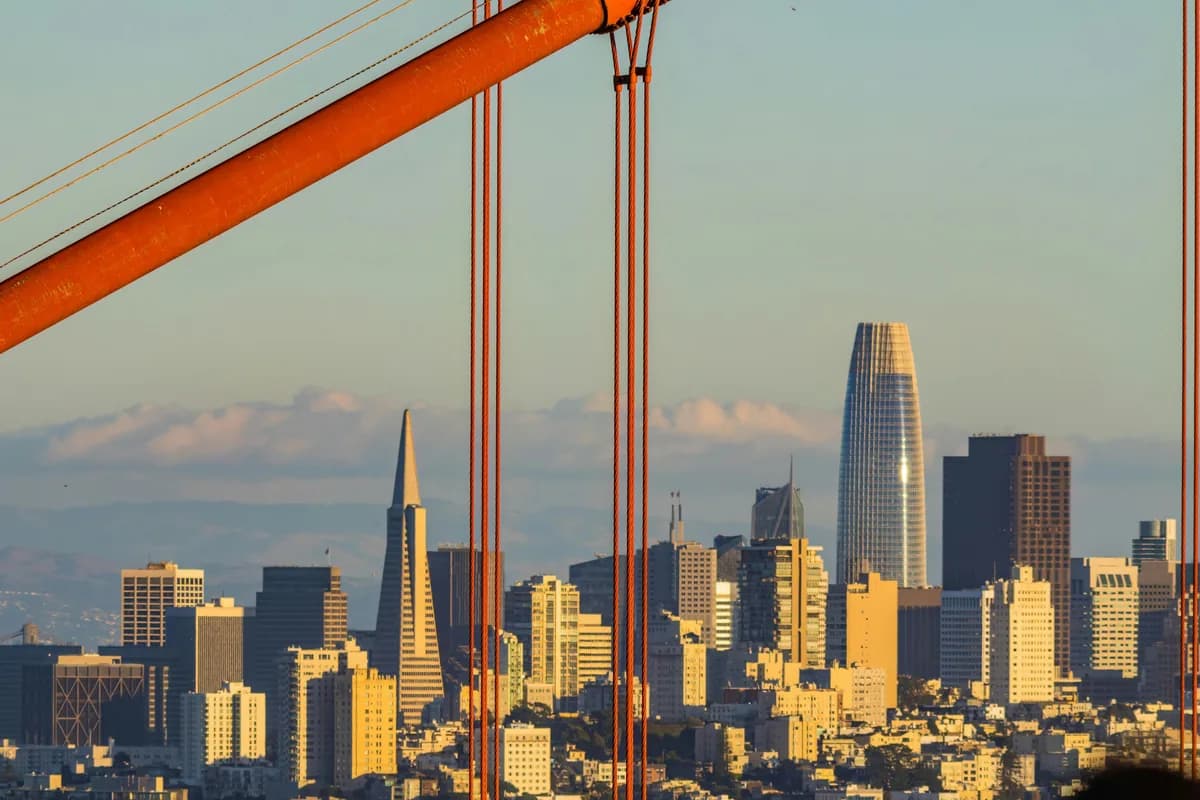 Urban skyline viewed through bridge cable wires with golden sunlight