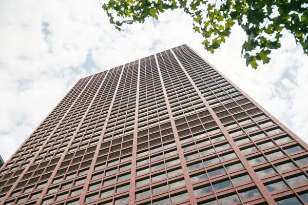 Tall residential high-rise building with grid pattern windows against cloudy sky