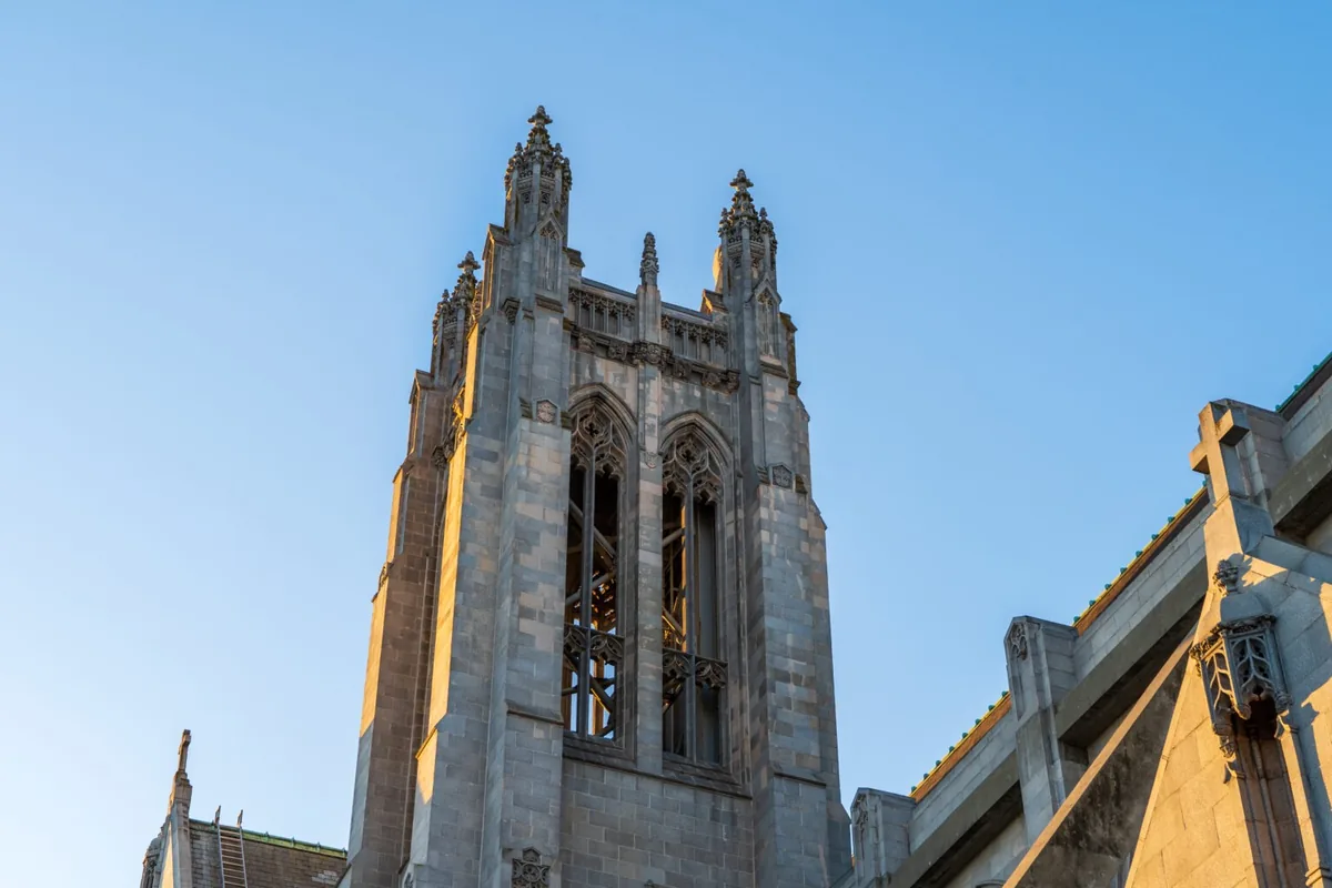 Gothic stone church tower with ornate spires against clear blue sky