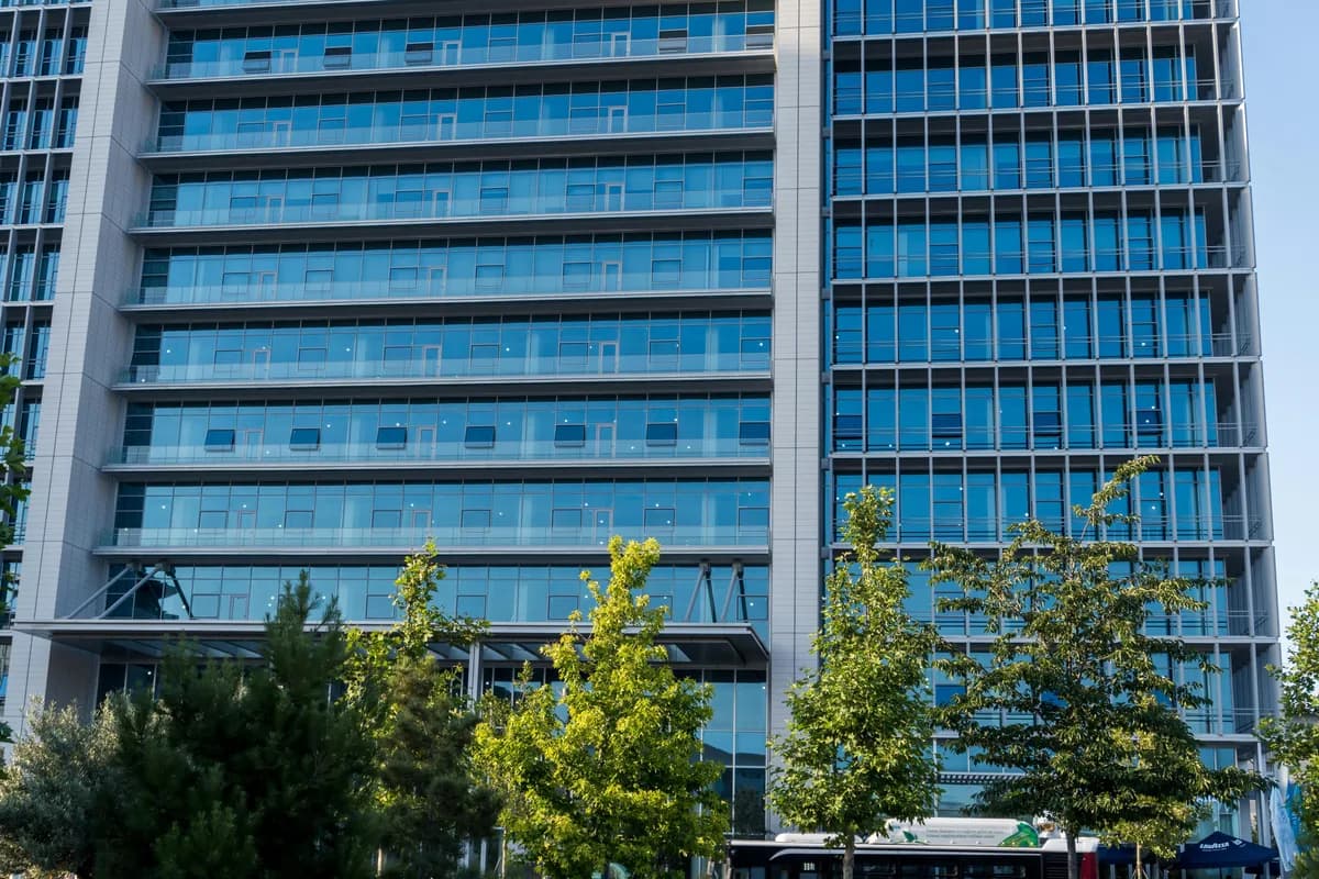 Modern office building facade with extensive glass windows and green landscaping