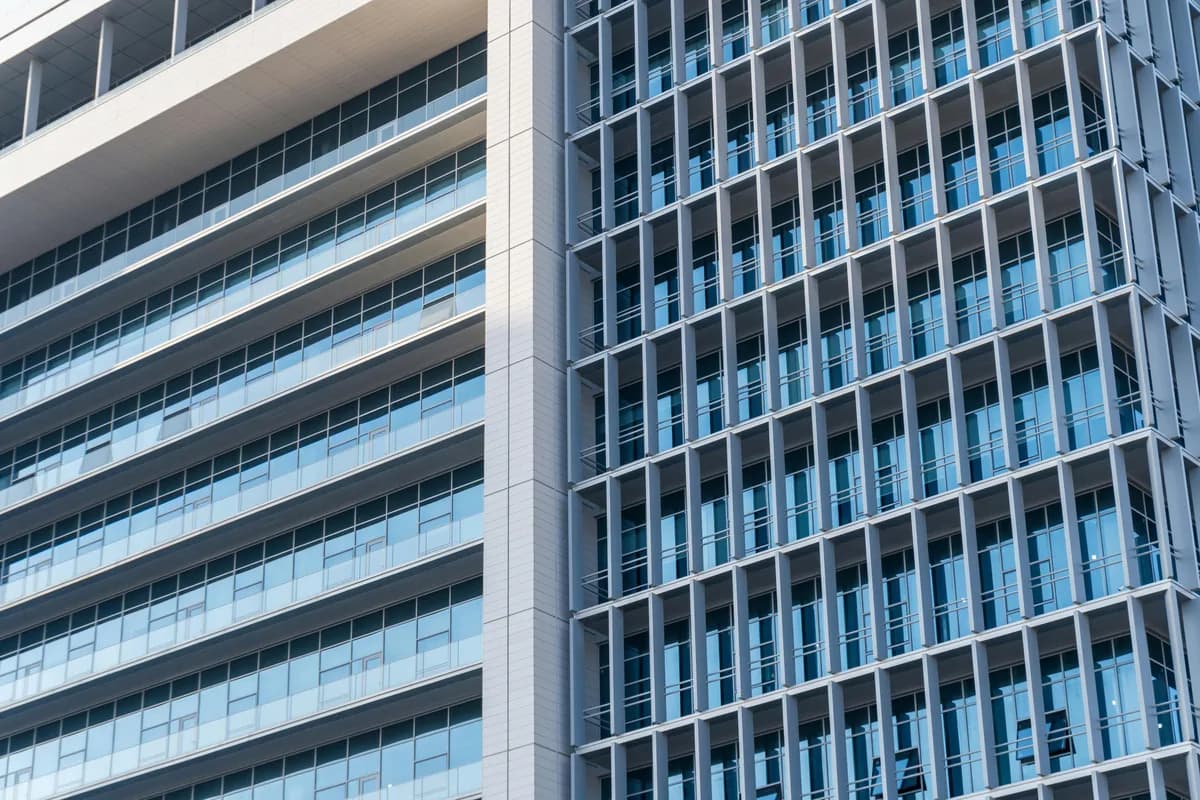Modern high-rise building facade with rows of clean glass windows and white frames