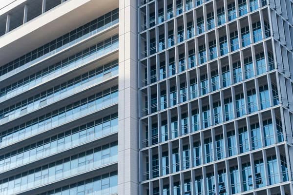 Modern high-rise building facade with rows of clean glass windows and white frames