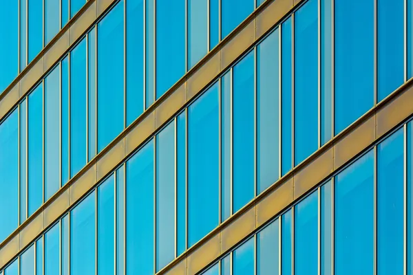 Modern glass building facade with blue reflective windows and metal frames
