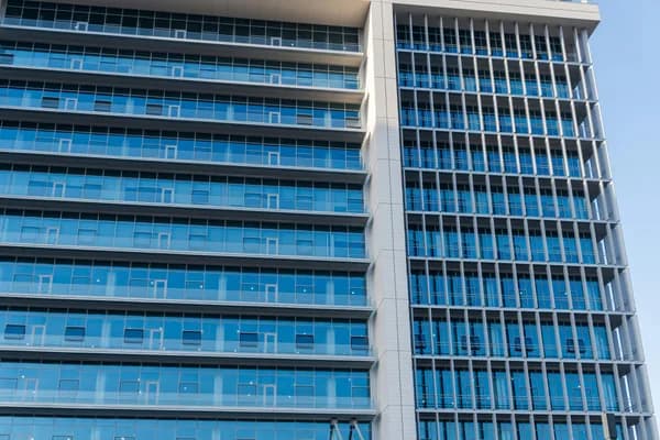 Modern high-rise building exterior with reflective blue glass windows and metal framing