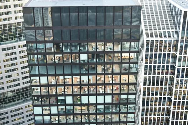 Modern office building facade with numerous reflective glass windows and dark frames
