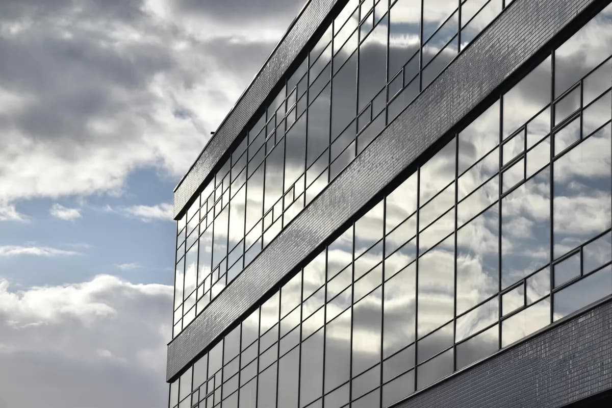 Modern office building facade with reflective glass windows and cloud reflections