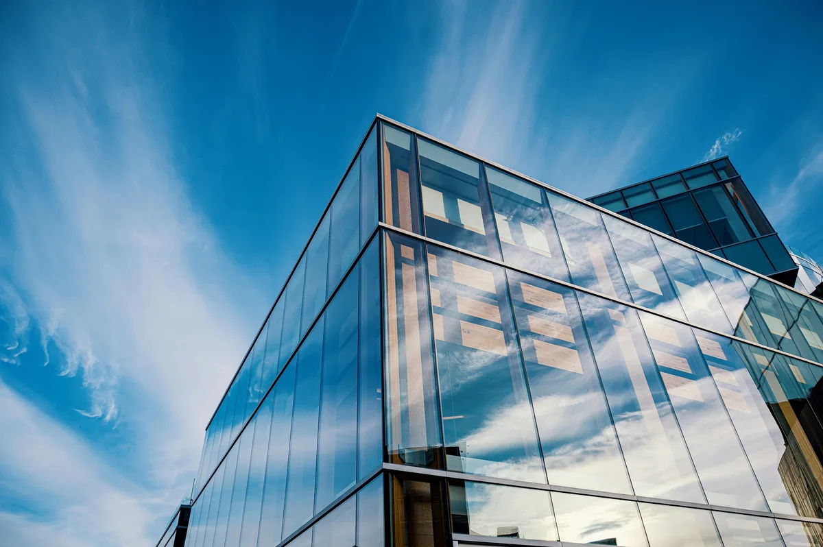 Modern glass building exterior with reflective windows against blue sky