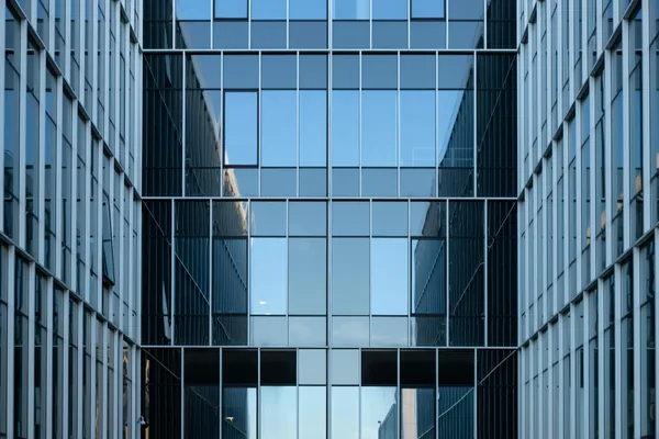 Modern glass-fronted building courtyard with symmetrical gridded window facades
