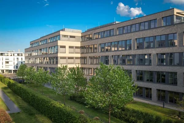 Modern multi-story brick building with extensive windows and manicured landscaping