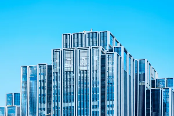 Modern commercial building facade with numerous reflective glass windows and vertical architectural elements