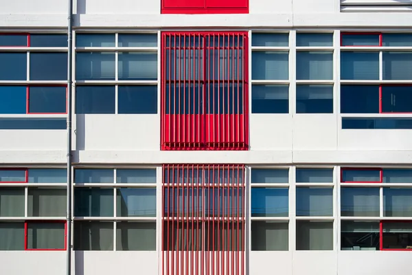 Modern office building facade with rows of windows and red metal railings