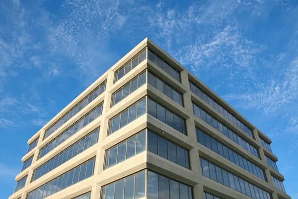 Modern multi-story office building with clean glass windows and light facade