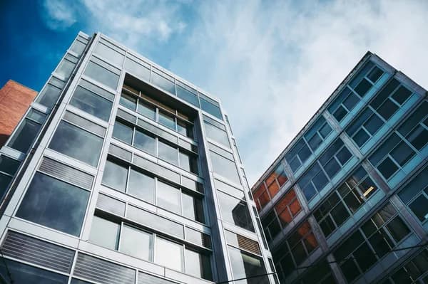 Modern glass-facade buildings photographed from below against blue sky