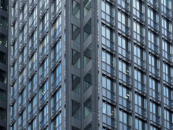 Modern high-rise building facade with repetitive rows of glass windows and metal framework