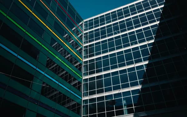 Modern glass office buildings with geometric window grid patterns and colored accent lines