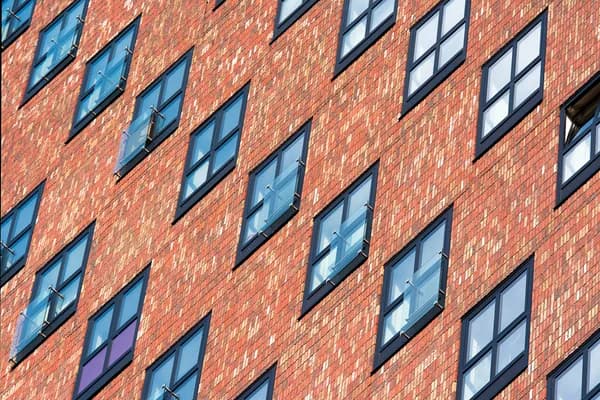 Modern brick building facade with rows of clean windows and dark frames