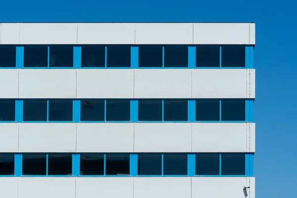 Modern multi-story building facade with blue columns and large windows
