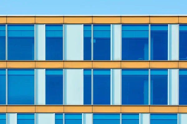 Modern office building facade with rows of large blue-tinted windows