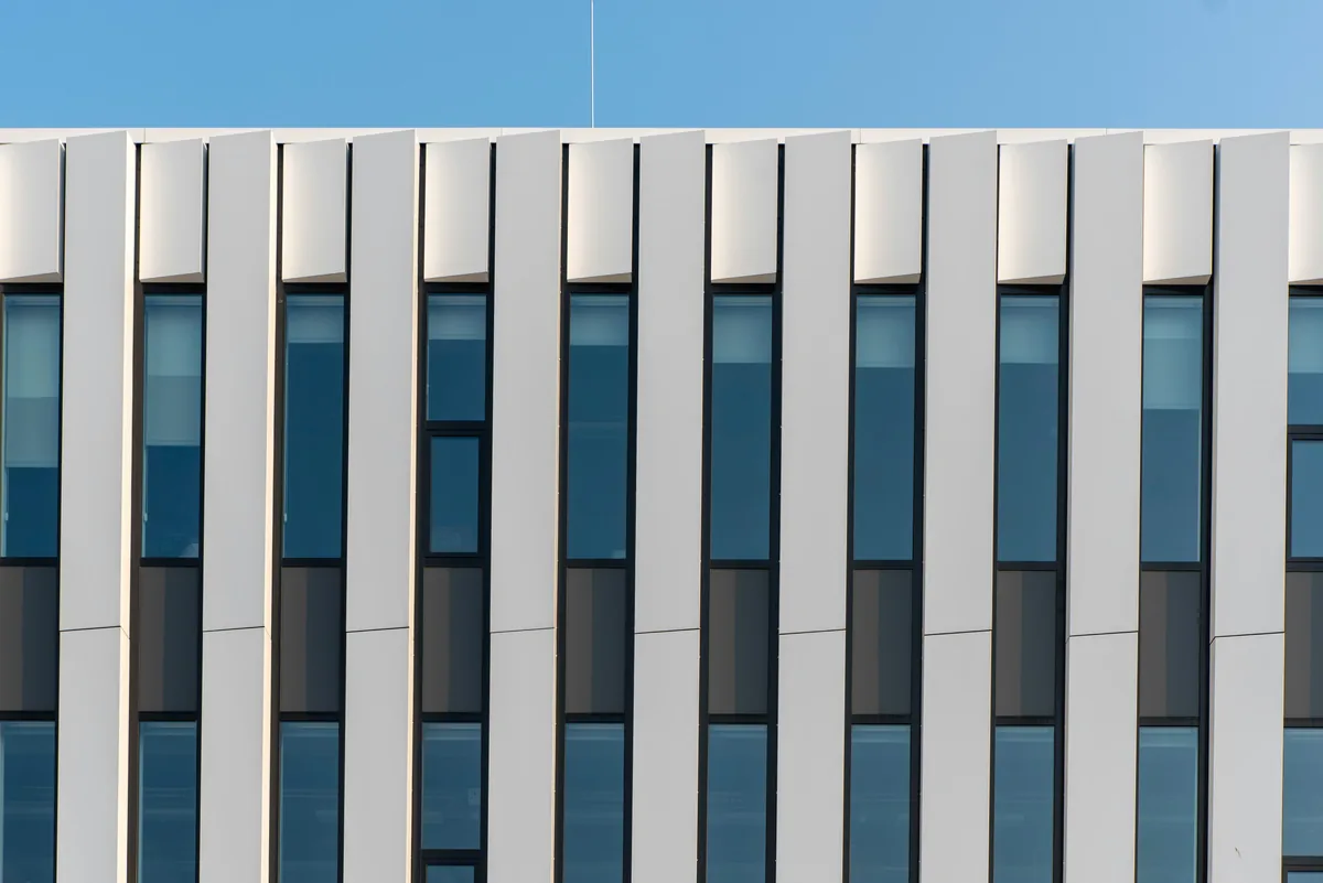 Modern office building facade with vertical white panels and blue-tinted windows