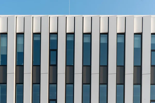 Modern office building facade with vertical white panels and blue-tinted windows