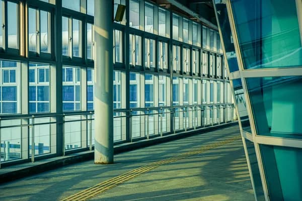 Modern interior corridor with floor-to-ceiling windows and sunlight streaming across floor