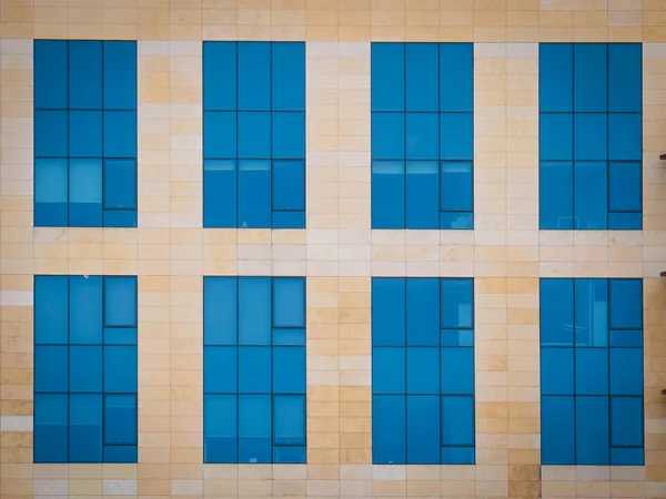 Modern building facade with repeating pattern of blue-tinted windows and tiles