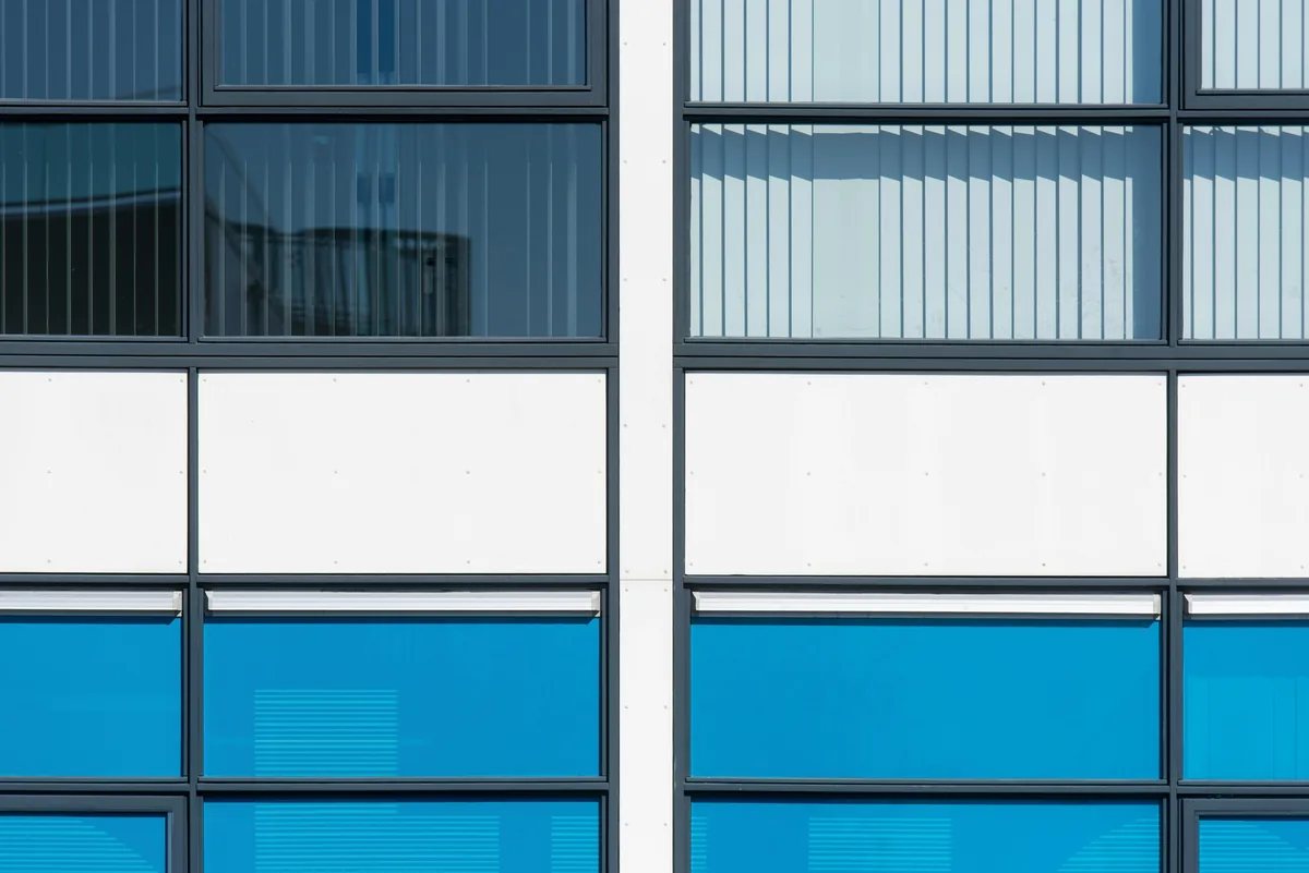 Modern building facade with reflective glass windows and blue panels
