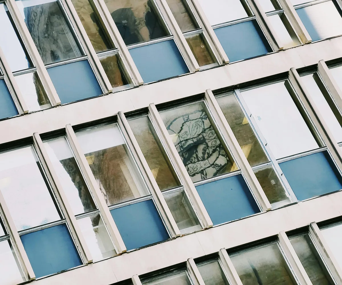 Dirty apartment building facade with blue-tinted windows needing professional cleaning