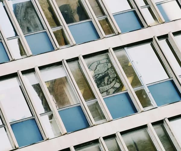 Dirty apartment building facade with blue-tinted windows needing professional cleaning