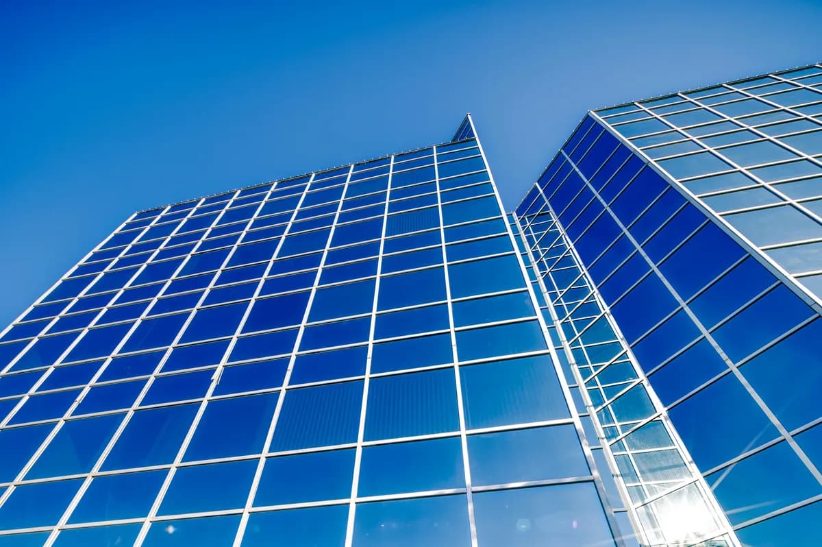Modern glass skyscraper with blue tinted windows and white metal framework