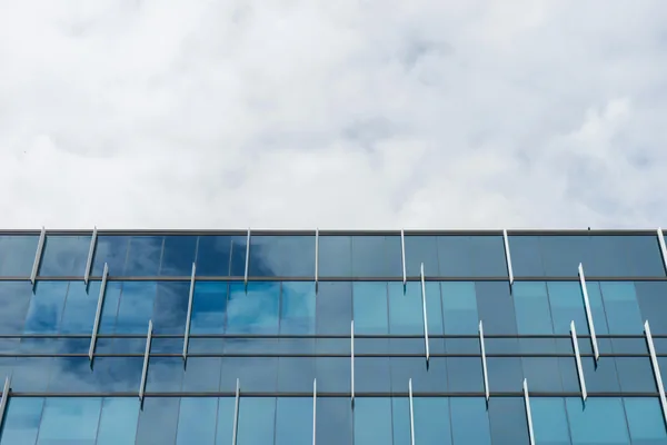 Modern glass building facade with reflective windows and metal framework