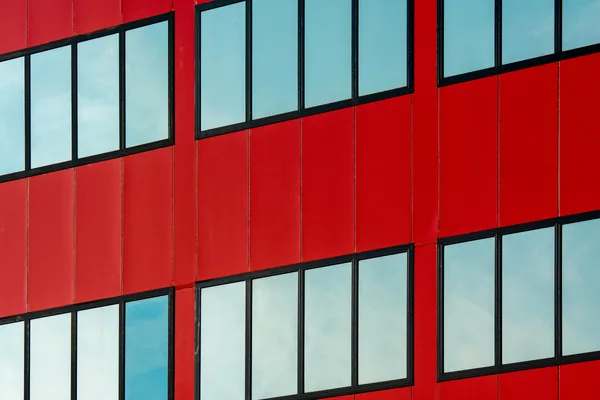 Modern red building facade with clean windows and black frames