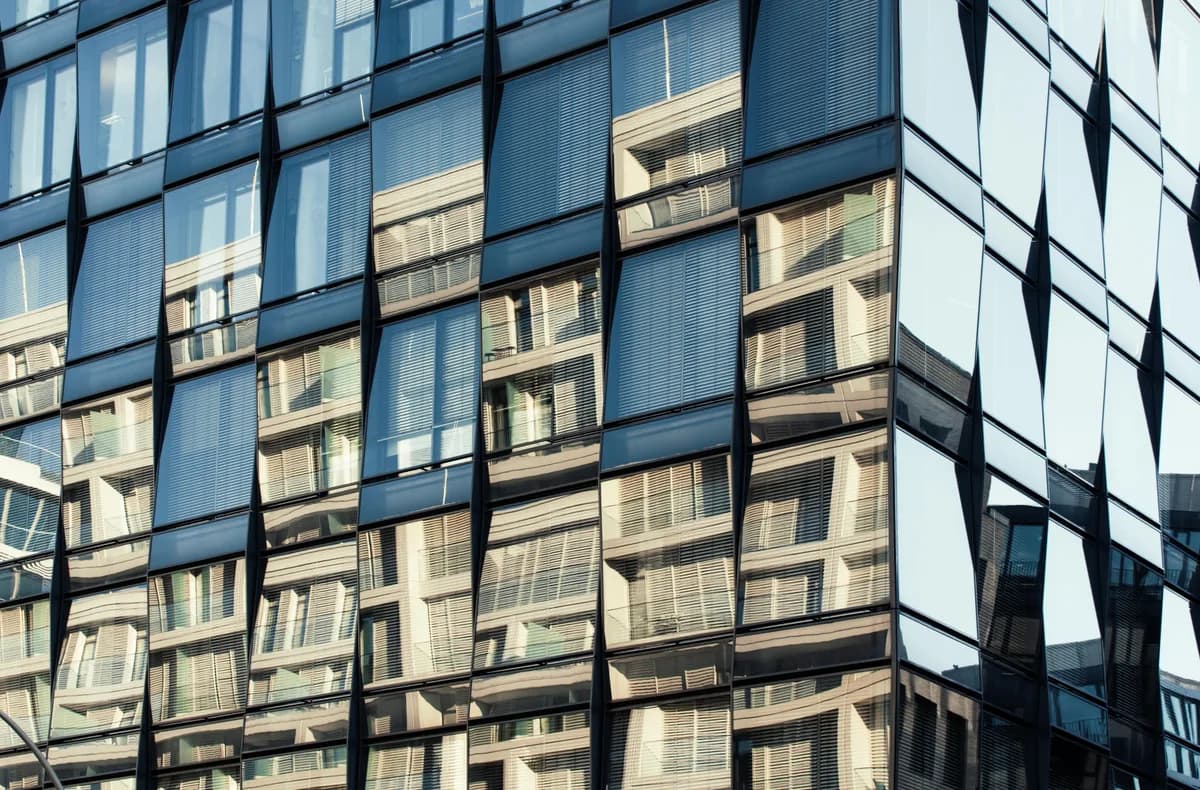 Modern office building facade with reflective glass windows and venetian blinds