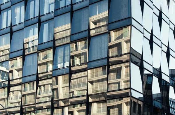 Modern office building facade with reflective glass windows and venetian blinds