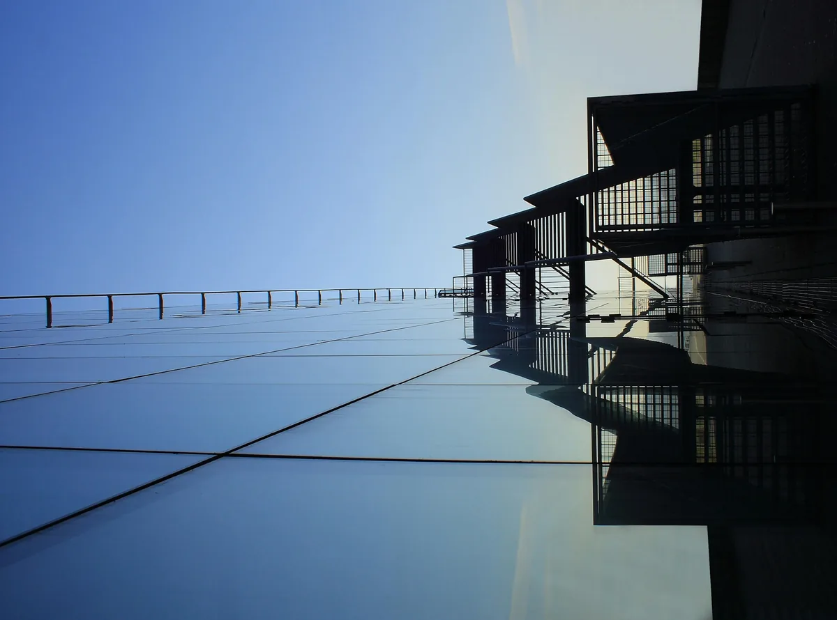 Modern building structure with glass panels reflected in still water surface