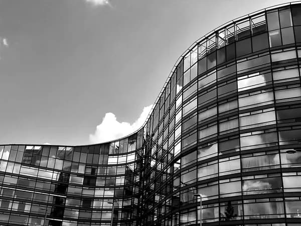 Modern curved glass building exterior with gridded windows and metal framework