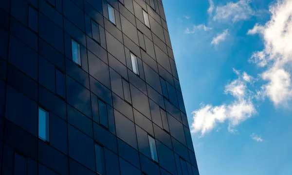 Modern glass office building exterior with clean reflective windows and blue sky