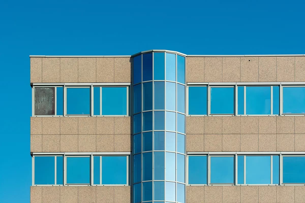 Modern office building facade with rows of large windows and blue glass
