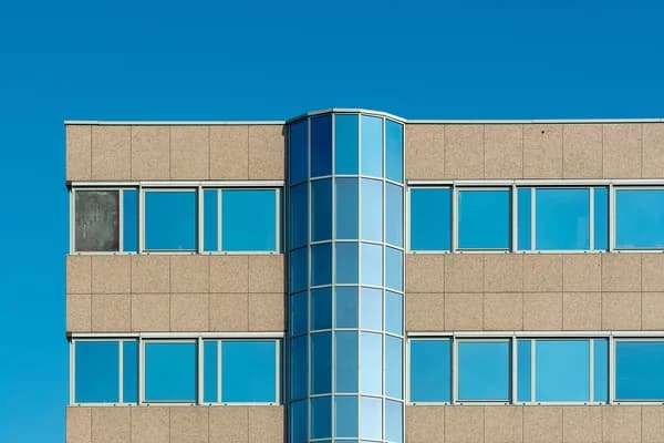 Modern office building facade with rows of large windows and blue glass