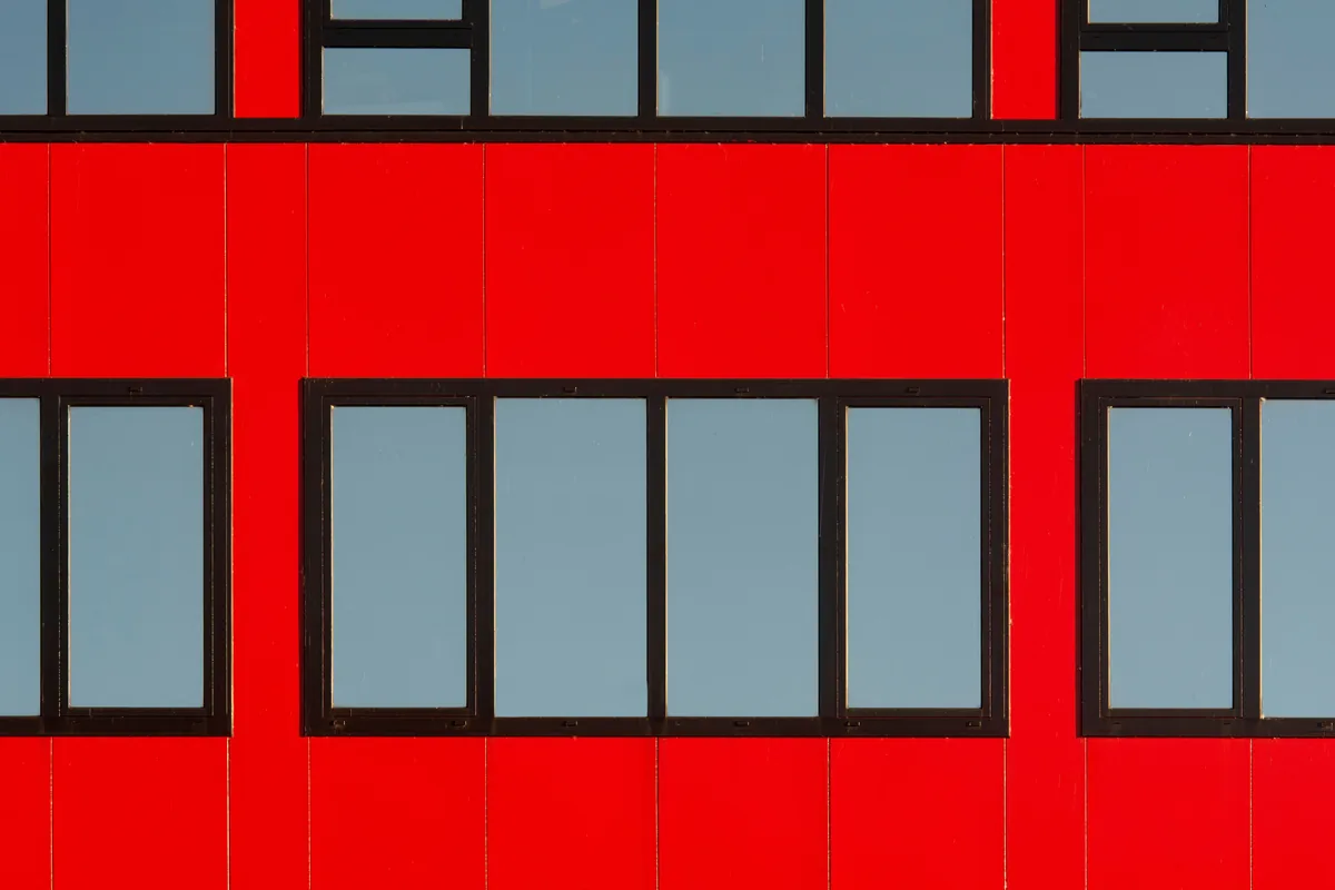 Modern building facade with red panels and black-framed windows
