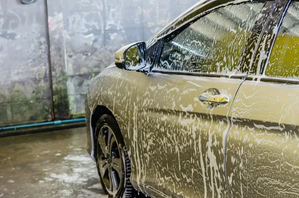 Vehicle being washed with water stream during professional cleaning service