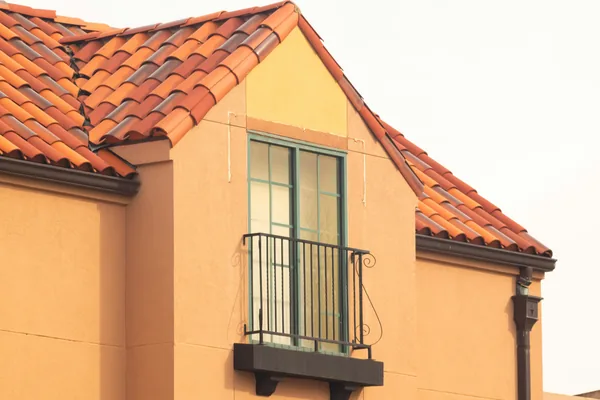 Mediterranean-style building exterior with large window and decorative balcony railing