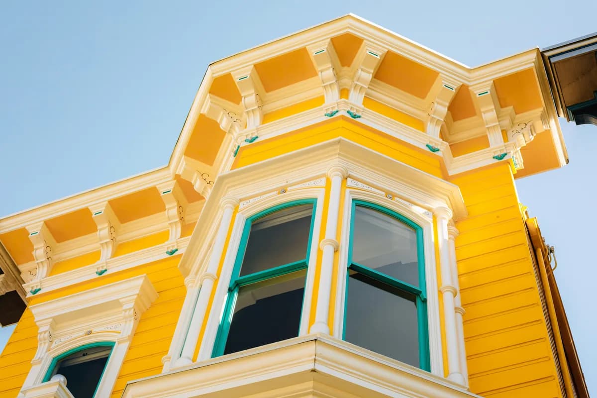 Bright yellow Victorian building facade with turquoise-framed windows and ornate details