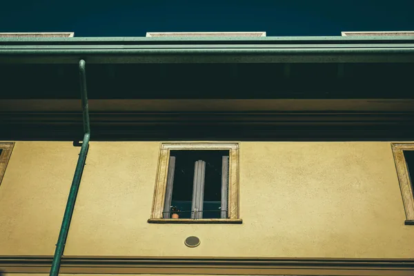 residential building exterior with yellow facade and green drainpipe
